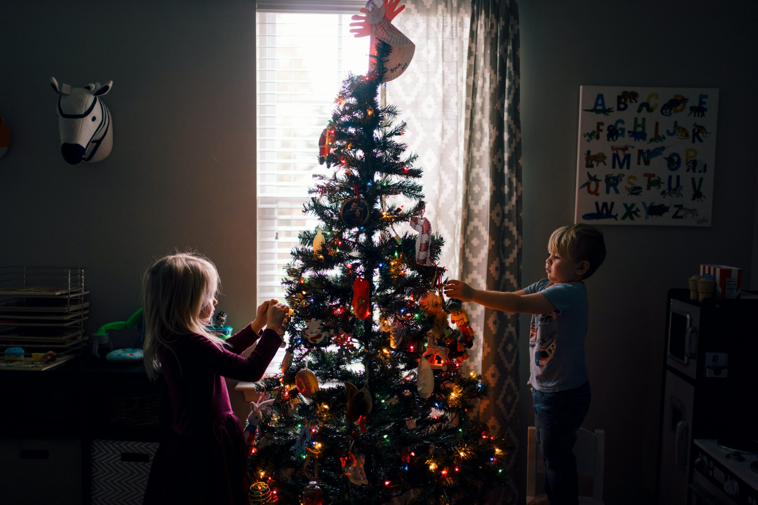 Kinder schmücken den bunten Weihnachtsbaum.